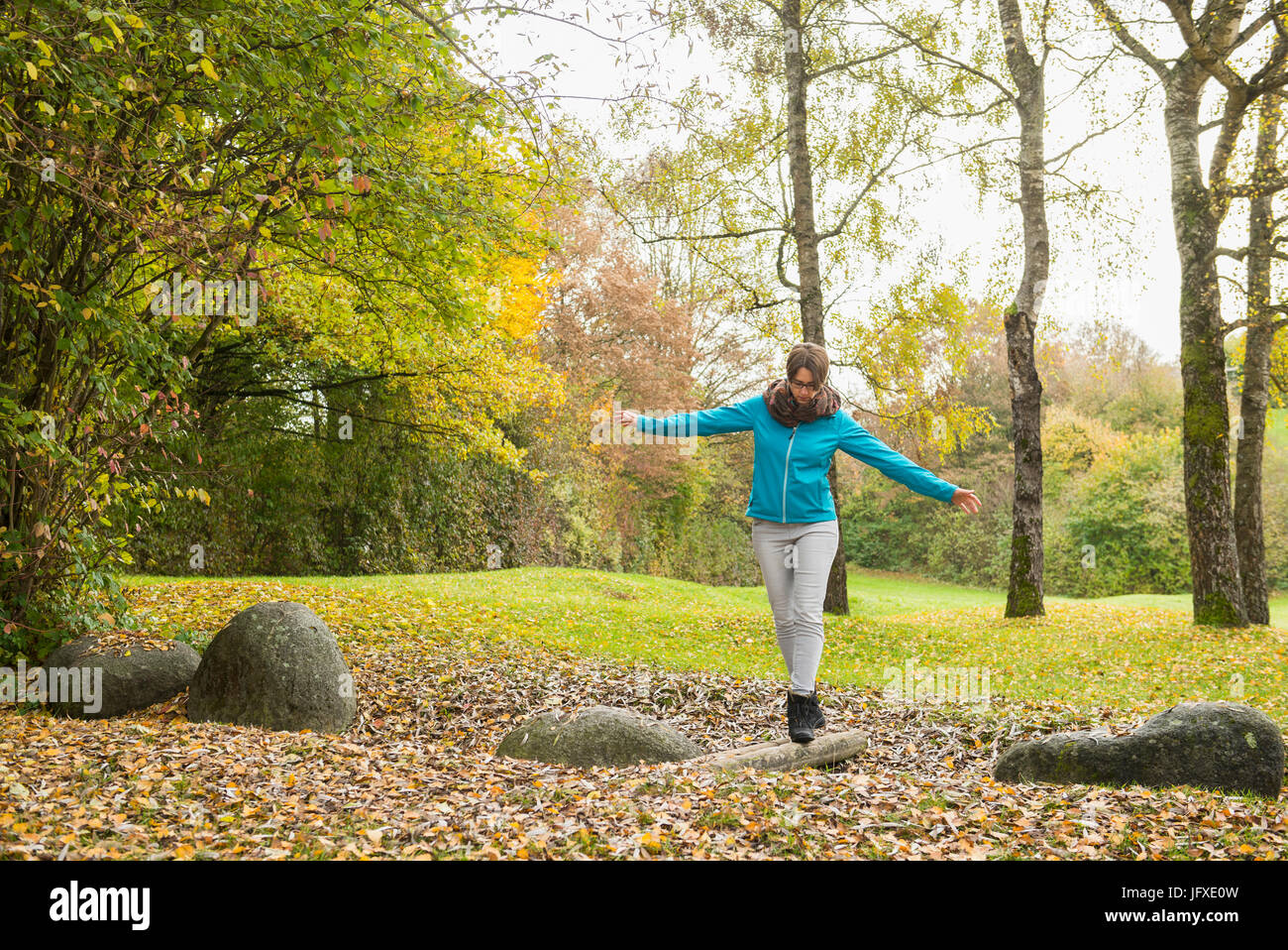 Frau balancieren auf Stamm in Herbstlandschaft im Hintergrund Stockfoto