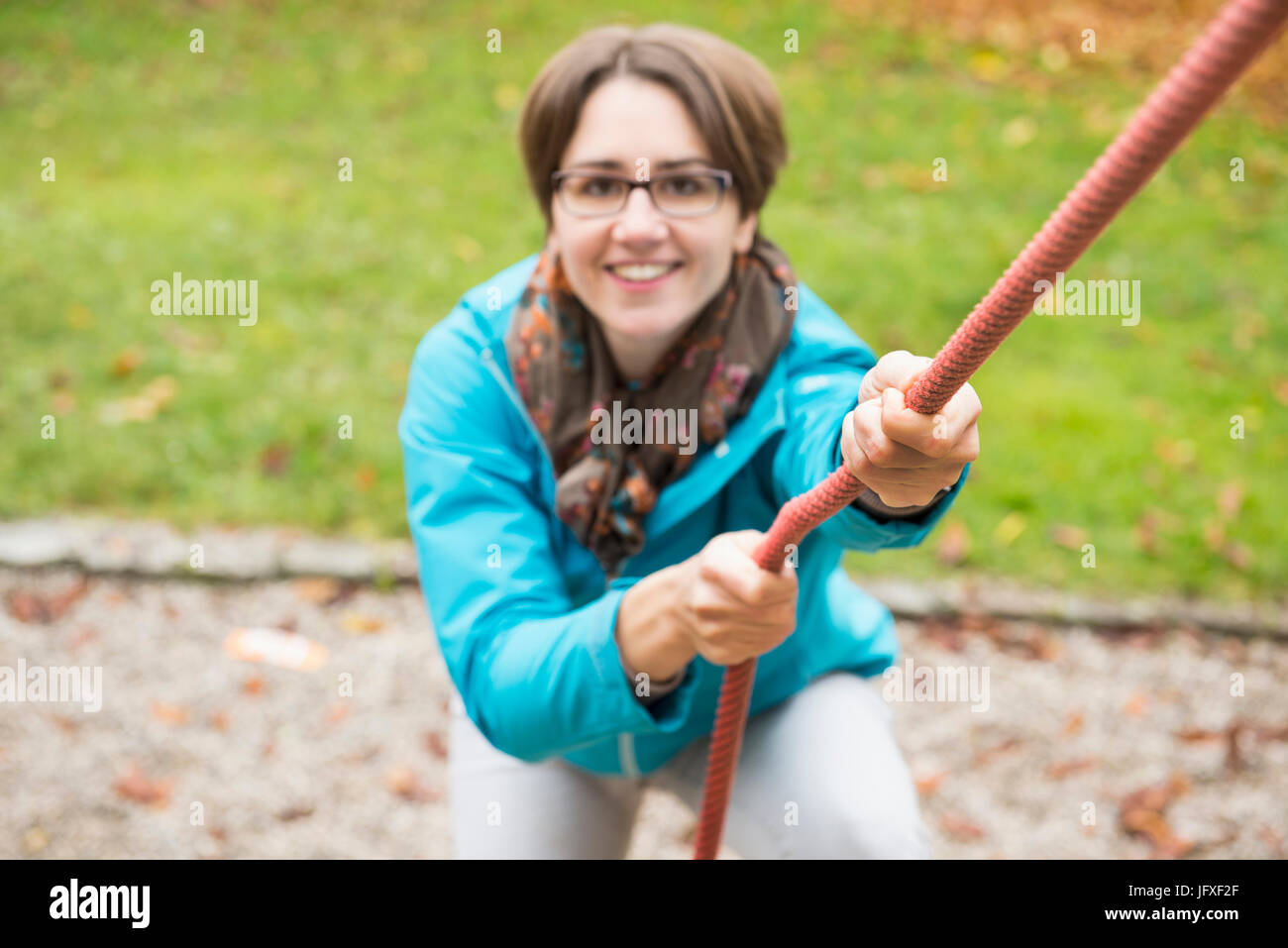 Frau zog sich nach oben an einem Seil von Spielgeräten in eine Herbstlandschaft Stockfoto