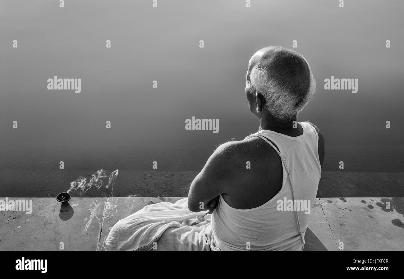 Ein Brahmane, hohe Kaste Hindus, beten zu Gott mit brennendem Weihrauch an seiner Seite und einen ruhigen Heiligen See in der Dämmerung in Pushkar, Rajasthan, UK. Stockfoto