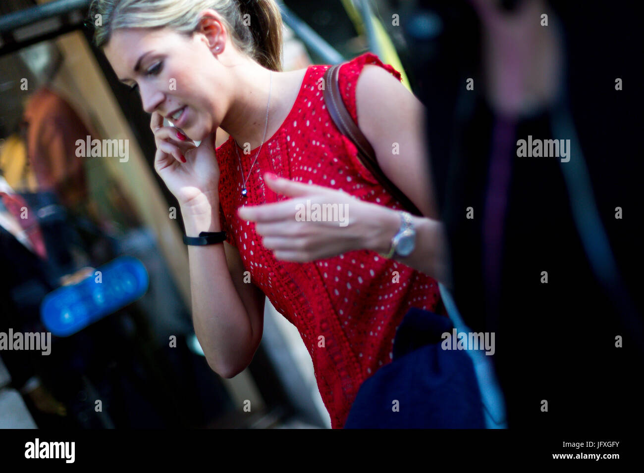 Eine Frau geht entlang einer belebten Straße in London, während auf ihrem Mobiltelefon sprechen Stockfoto