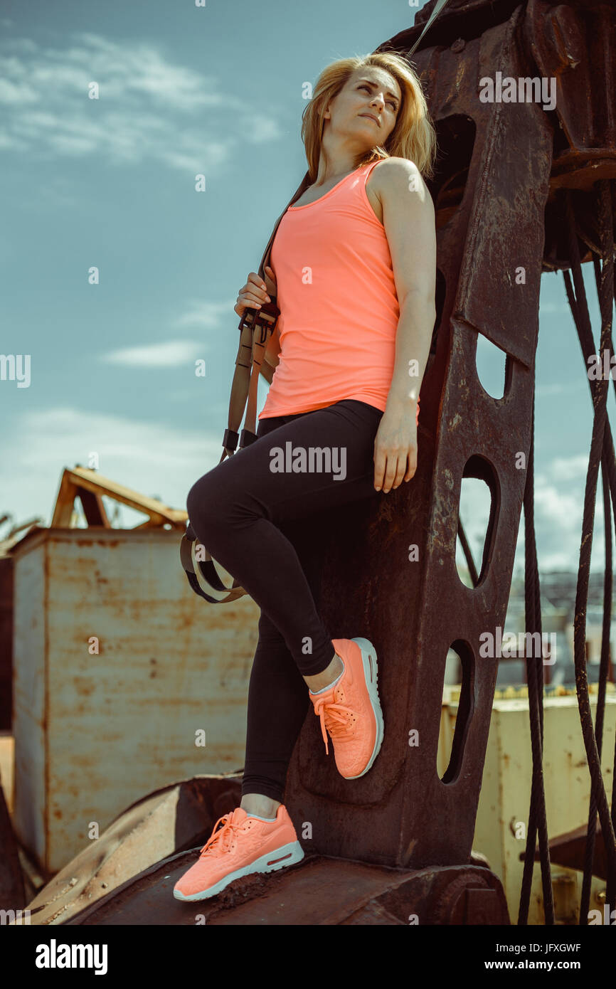 Schöne junge Frau in einem Orangen T-shirt mit Trx-Fitness-Riemen Stockfoto