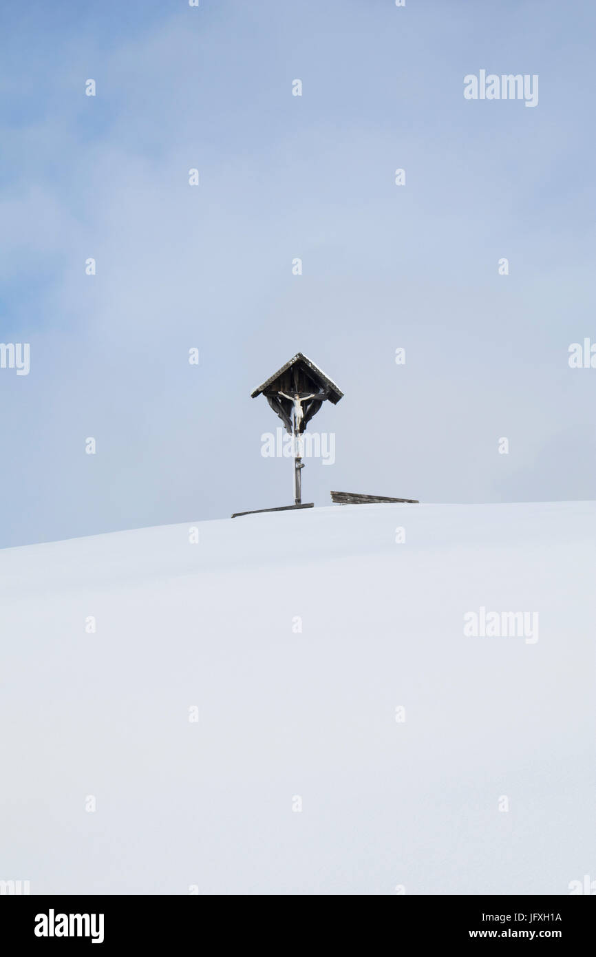 Kruzifix auf schneebedeckten Berg gegen Himmel mit Wolke Stockfoto