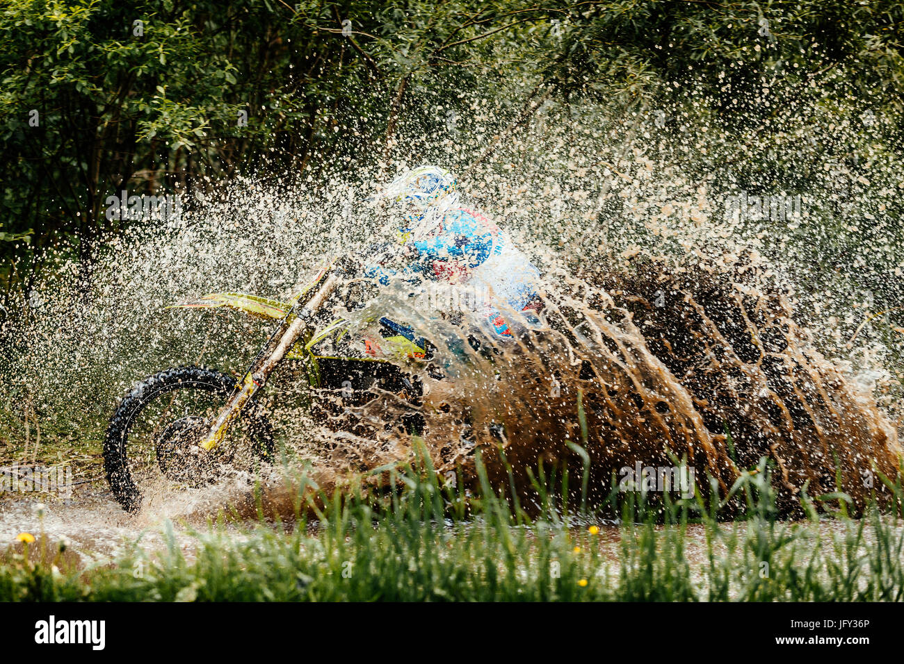 Motorrad-Fahrer Kreuze Pfütze Spritzer von Wasser und Schmutz Stockfoto
