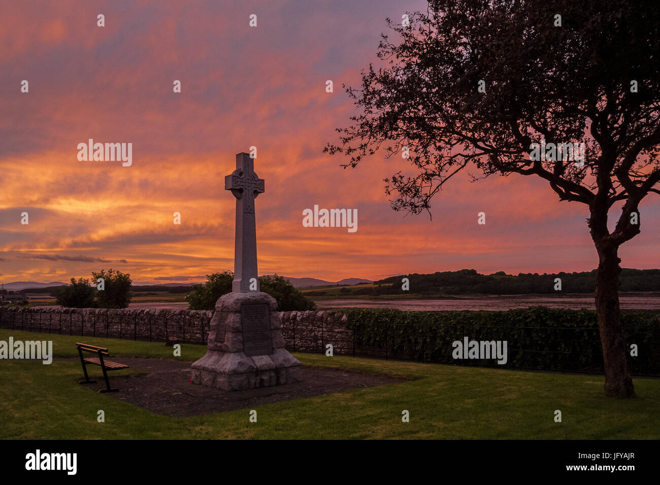 Angrenzend an ein Kriegerdenkmal für die gefallenen mit einer lebendigen Roter Himmel Sonnenuntergang und leere Vorland hinter leeren Platz. Stockfoto