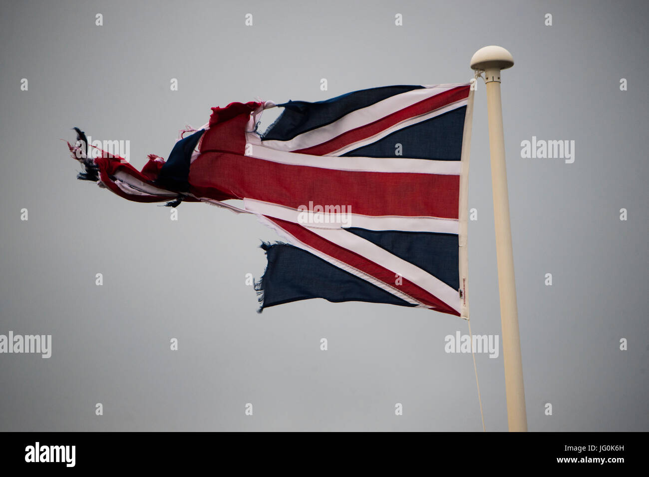 Brechen des Begriffs Vereinigtes Königreich: eine misshandelte und zerrissen und ausgefranste Union Jack Banner Flagge von Großbritannien, fliegen an einem grauen, bewölkten Tag, UK Stockfoto