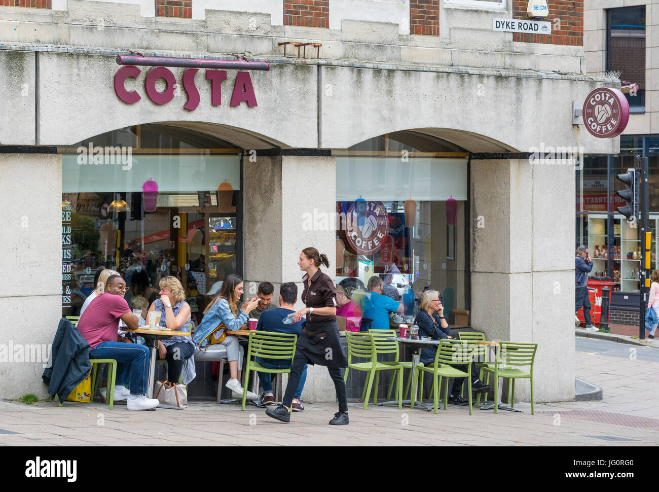 Menschen sitzen außerhalb einer Costa Coffee Shop mit einer Kaffeepause. Stockfoto