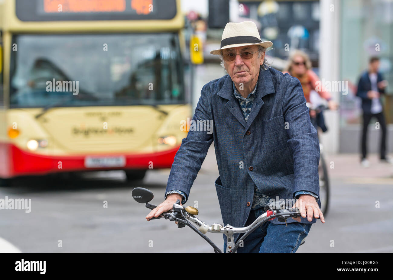 Stilvoll im Alter suave suchen mittleren bis älteren Mann in einem Sommer Hut und Denim Outfit Radfahren auf einer viel befahrenen Straße. Stockfoto