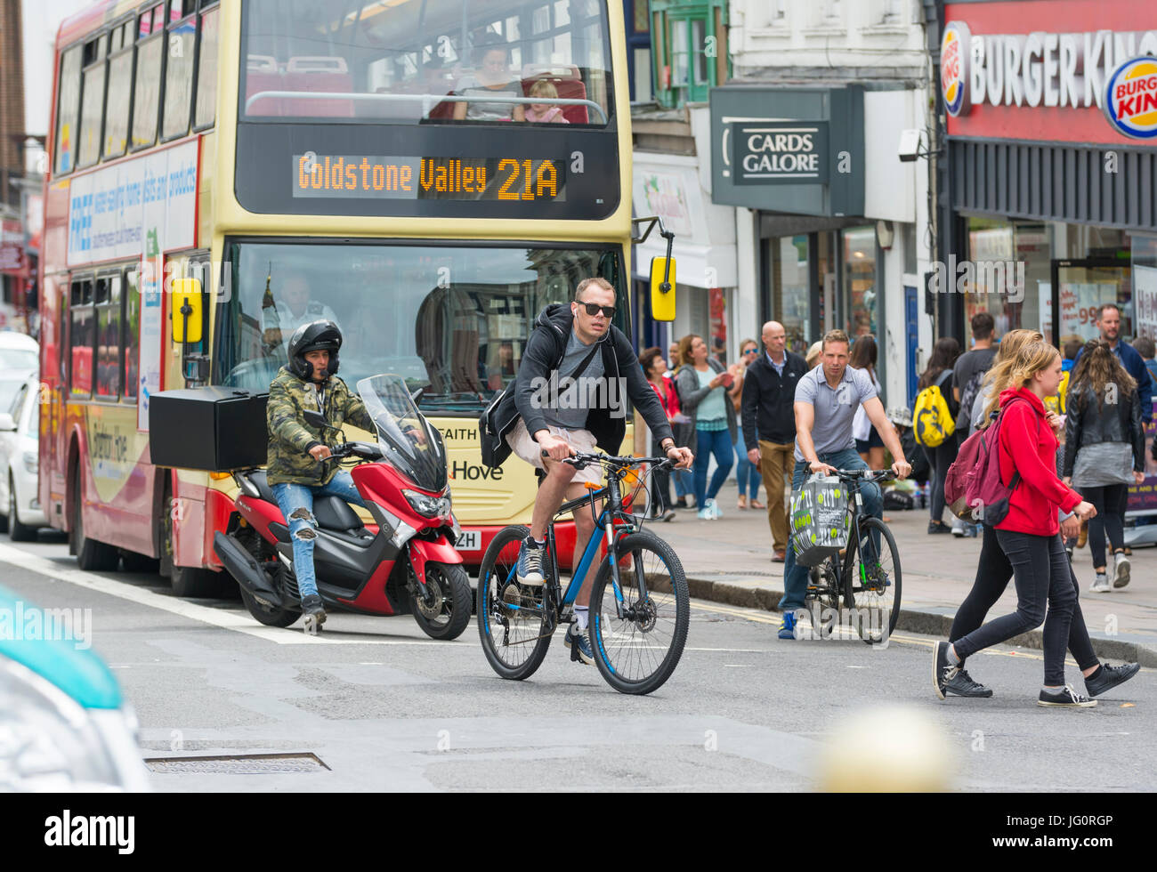 Radfahrer, die ein rotes Licht, während eine andere Radfahrer, Motorradfahrer und eine Bushaltestelle in der Zeile zu springen. Stockfoto