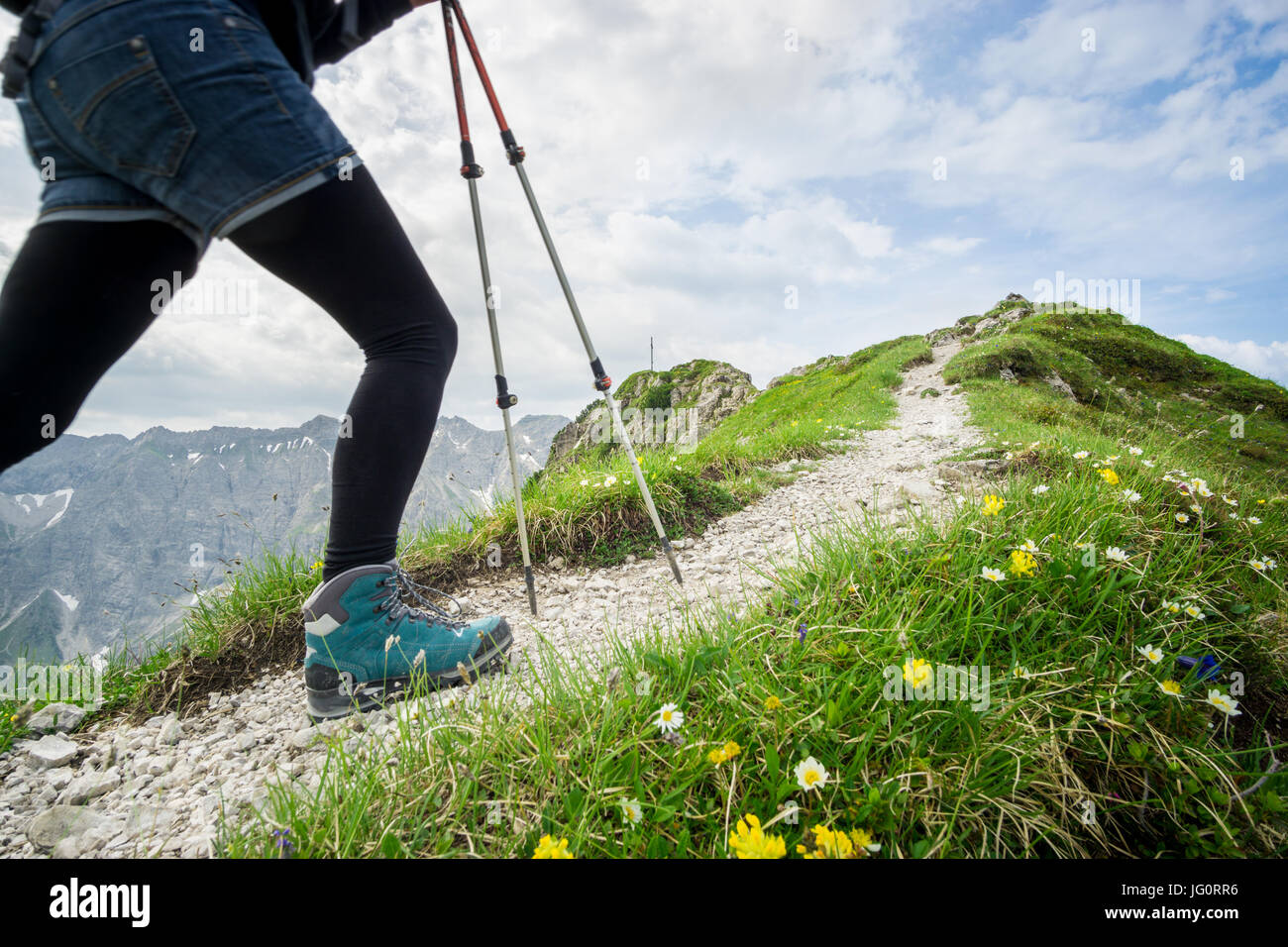 Frau läuft auf schmalen Bergweg mit Wanderstöcken. Stockfoto