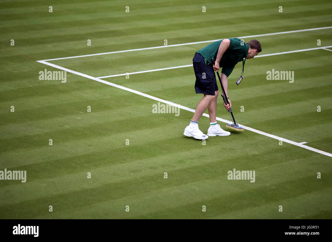 Ein Mitglied des Bodenpersonals malt die Zeilen vor Tag eins der Wimbledon Championships in The All England Lawn Tennis and Croquet Club, Wimbledon. Stockfoto