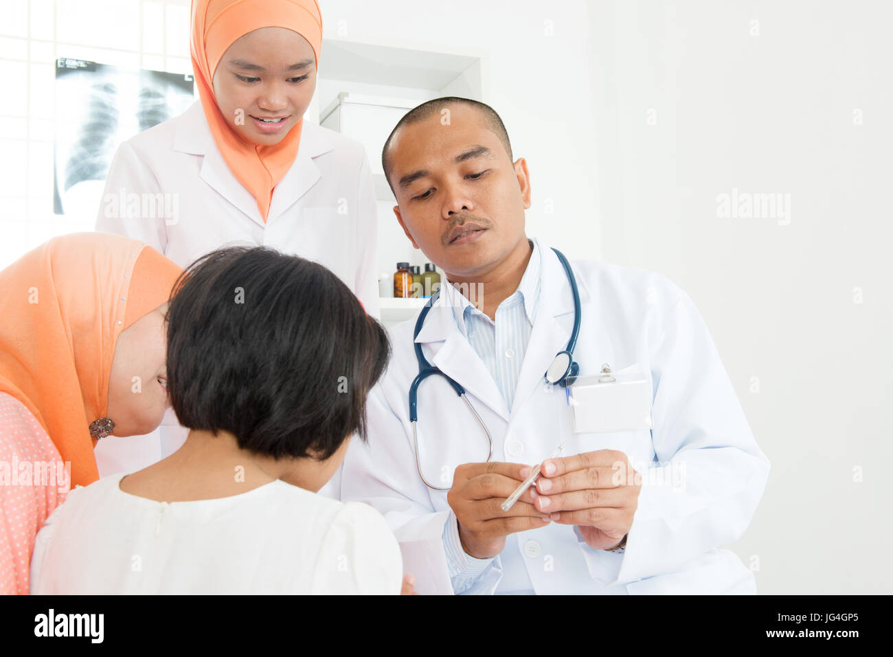 Überprüfung des kleinen Mädchens Temperatur am Krankenhaus Arzt.  Südostasiatische muslimischen Familie. Stockfoto