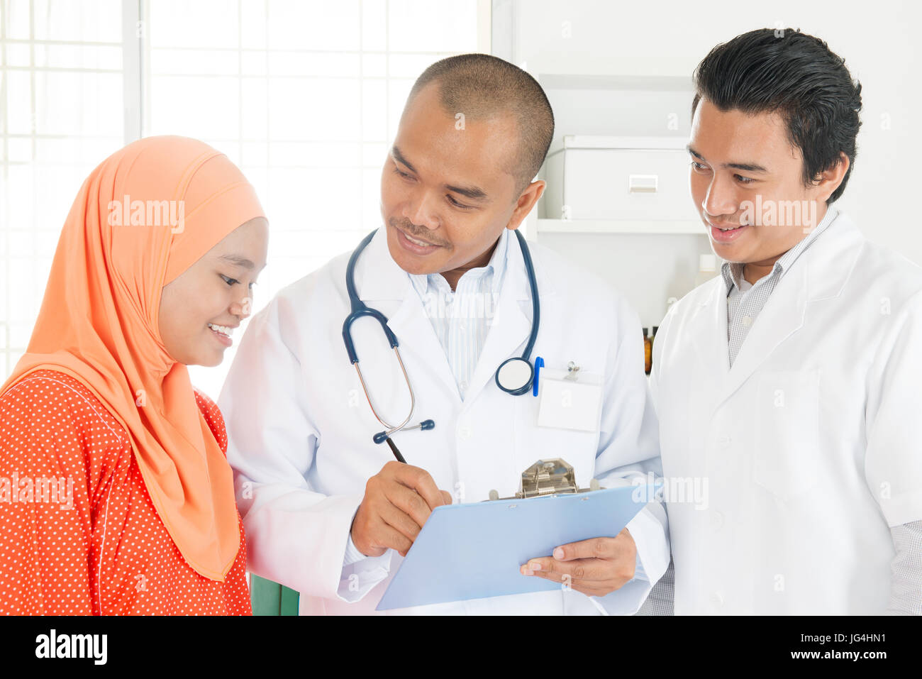 Ärzteteam Behandlungsmöglichkeiten mit dem Patienten besprechen. Südostasiatische muslimischen Menschen. Stockfoto