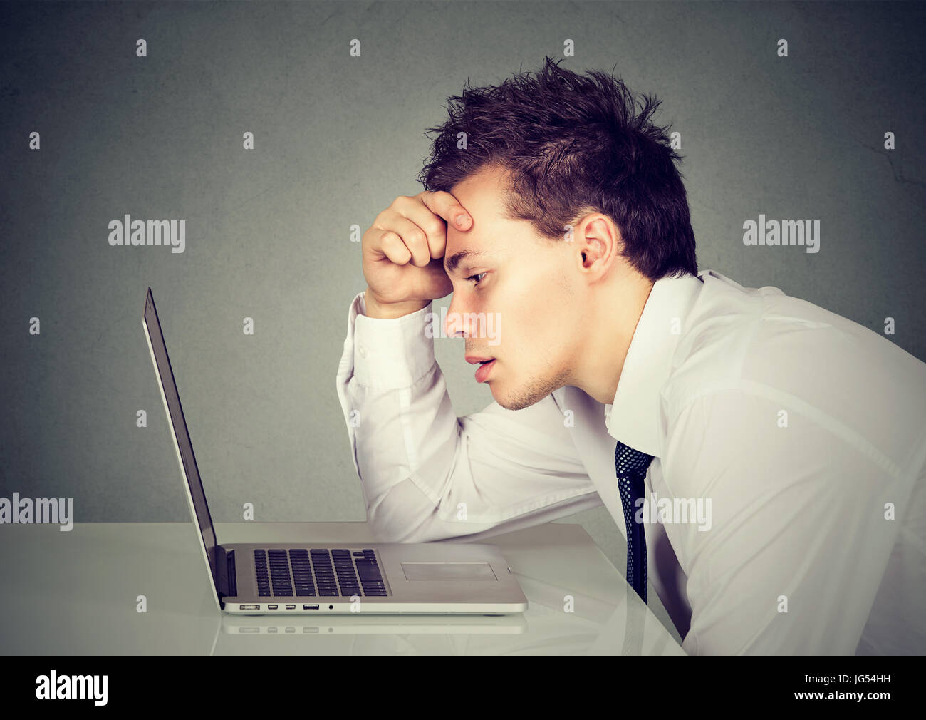 Unglücklich betonte traurigen Mann am Schreibtisch vor seinem Laptop sitzt Stockfoto