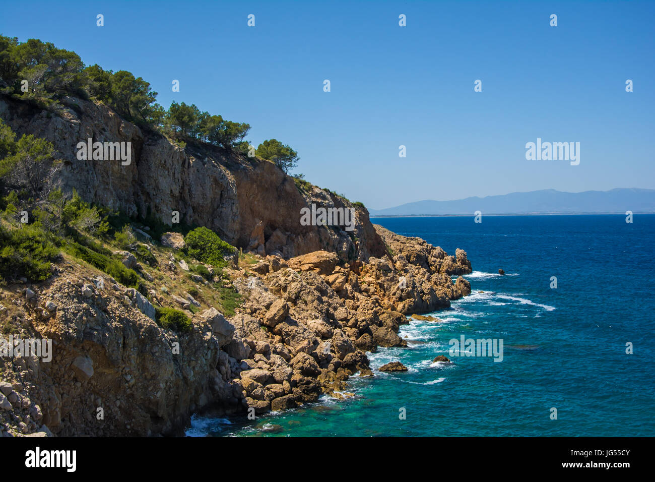 Felsen und Bäume gegen das Mittelmeer an einem sonnigen Tag an der Costa Brava Stockfoto