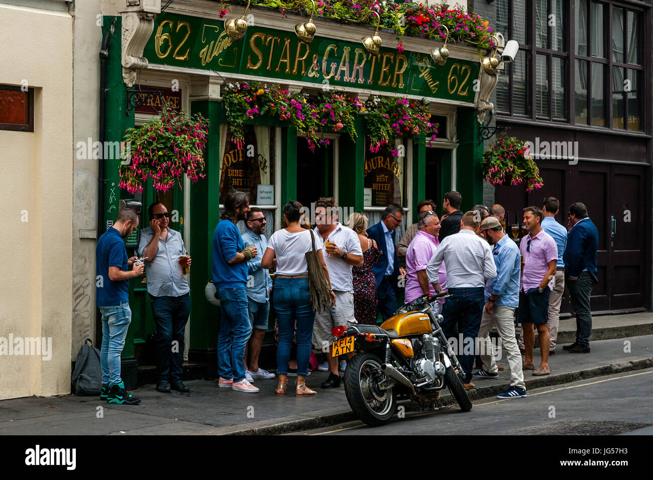 Eine große Gruppe von Menschen, die trinken außerhalb der Star und Strumpfband Pub, Poland Street, London, UK Stockfoto