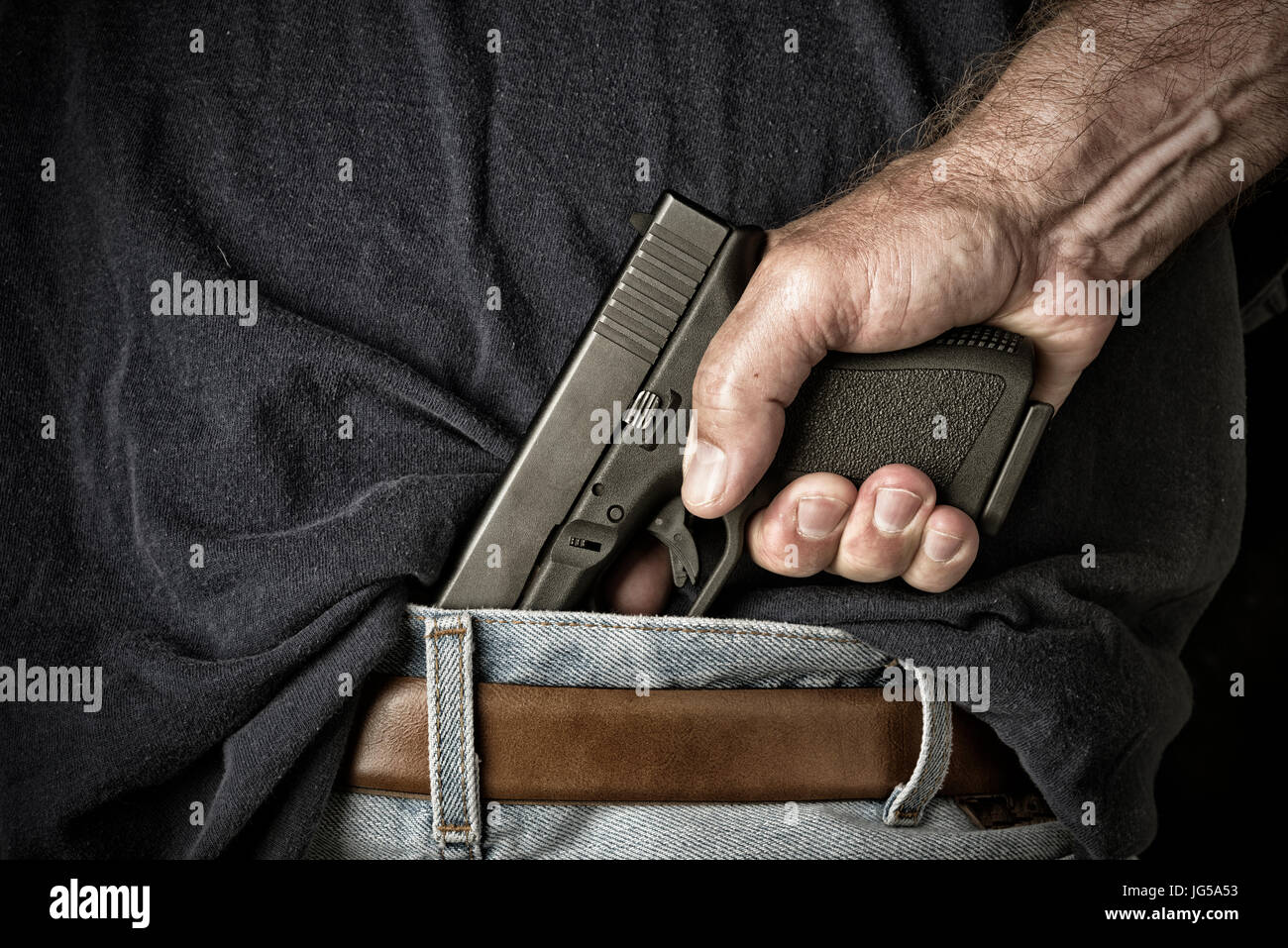 Ein Mann mit einer Pistole in seinem Bund greift den Griff in der Vorbereitung für das Ziehen der Waffe Stockfoto