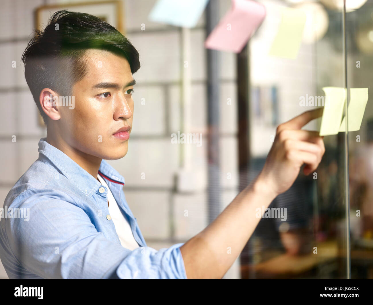 junge asiatische Geschäftsmann eng mit Blick auf die Schriften auf einem Zettel. Stockfoto