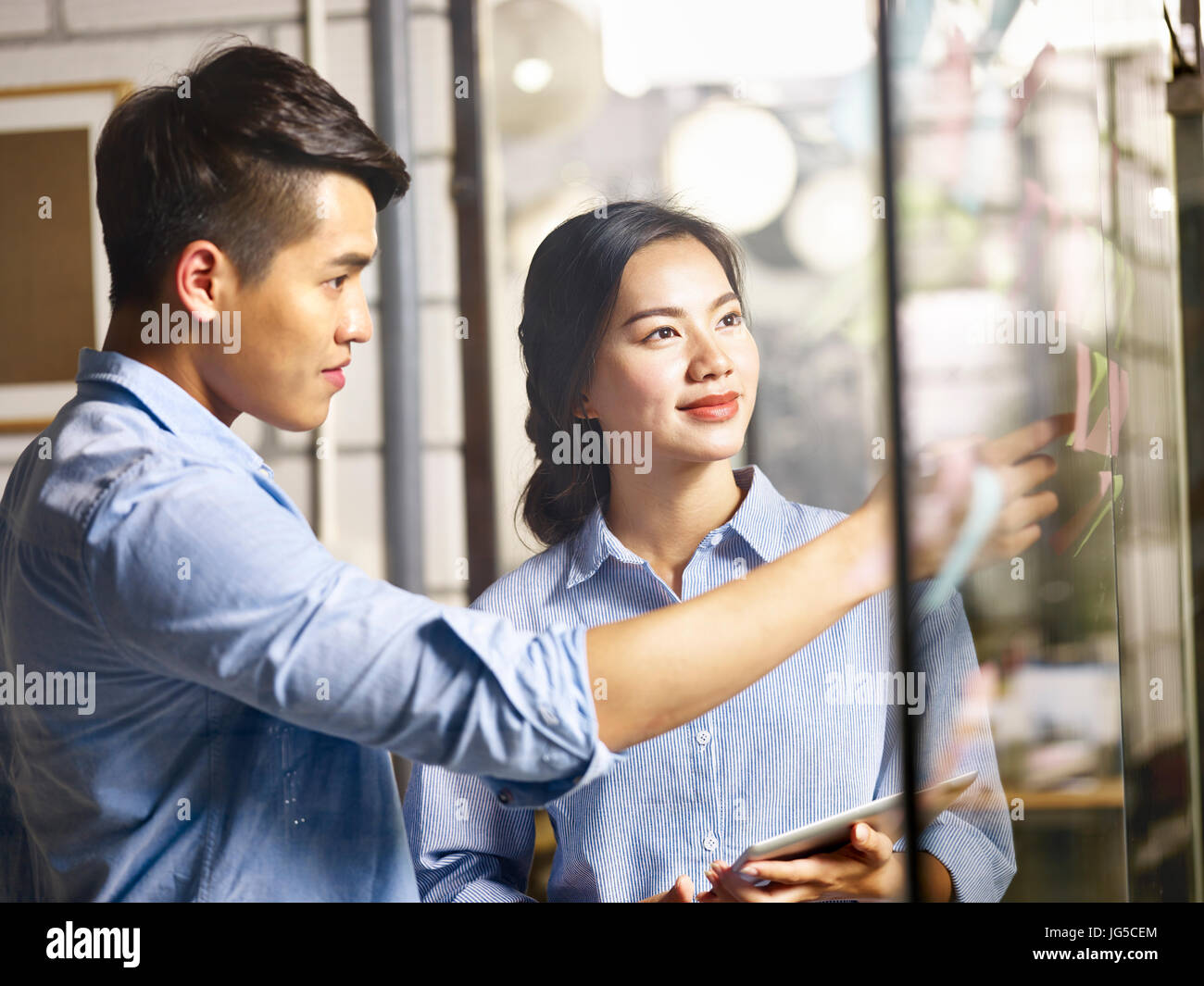 zwei asiatische Teamkollegen gemeinsam im Büro machen Business plan mit Haftnotizen und digital-Tablette. Stockfoto