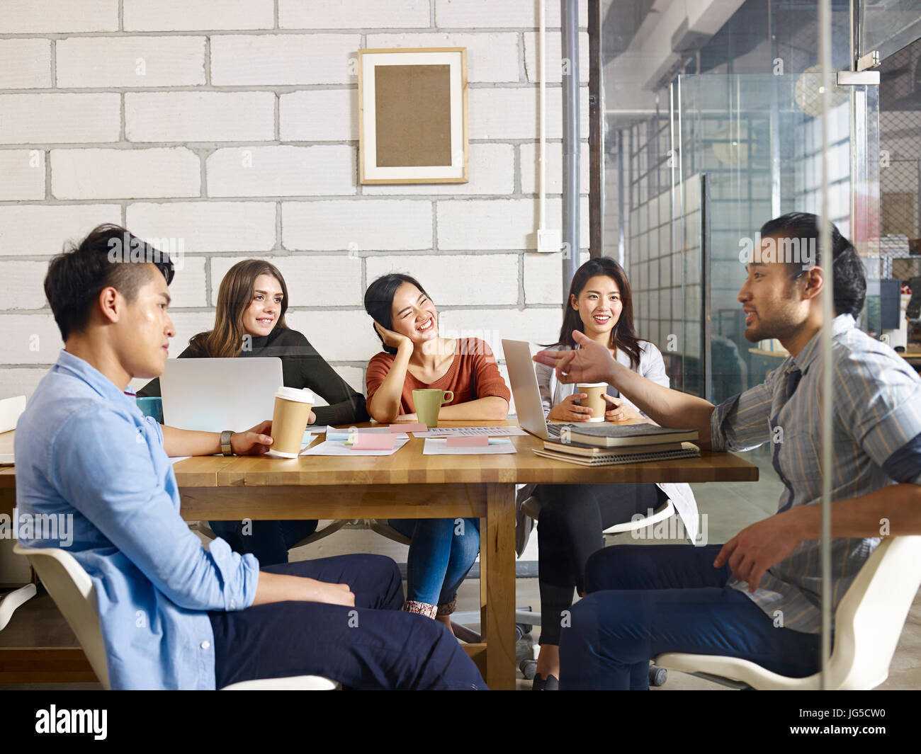 ein Team von multinationalen Menschen diskutieren Geschäft in Glas Tagungsraum. Stockfoto