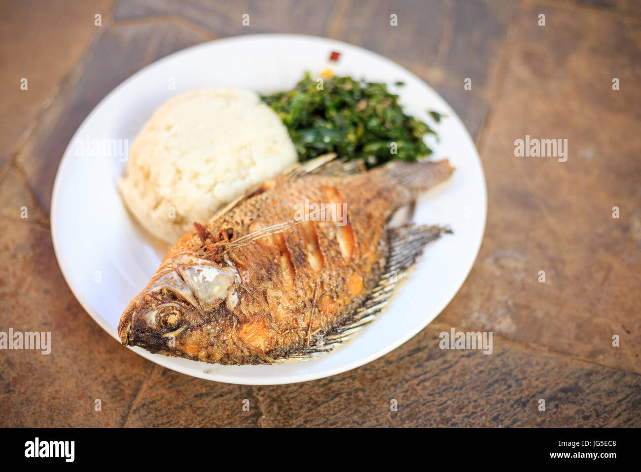 Traditionelle ostafrikanische Küche - Grüns in Kenia, Ugali und Fisch Stockfoto