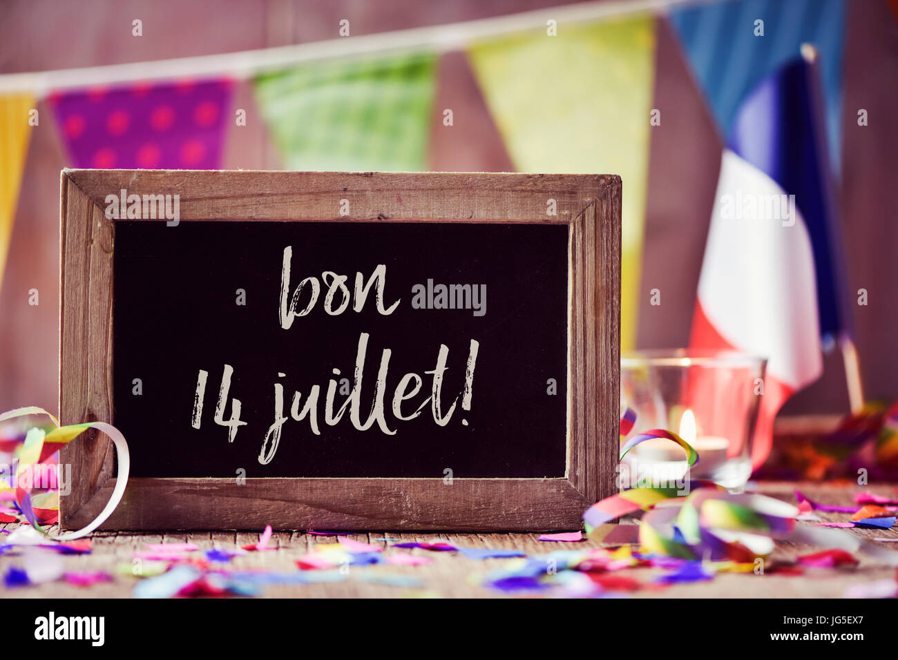 Tafel mit den Text Bon 14 Juillet, glücklich 14 Juli, der Tag von Frankreich, geschrieben in Französisch und eine Flagge von Frankreich, auf einem hölzernen Oberfläche sprink Stockfoto