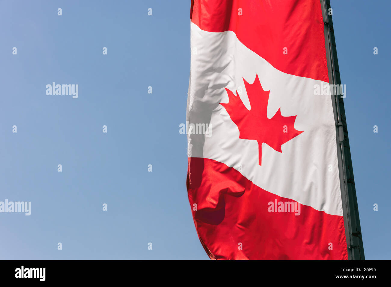 Vertikale schmale kanadische Flagge gegen blauen Himmel Stockfoto