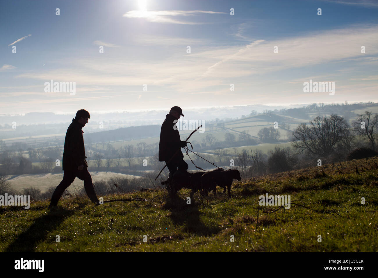 Zwei Männer, die ihren Hund spazieren gehen, in den Hügeln des ländlichen England. Stockfoto