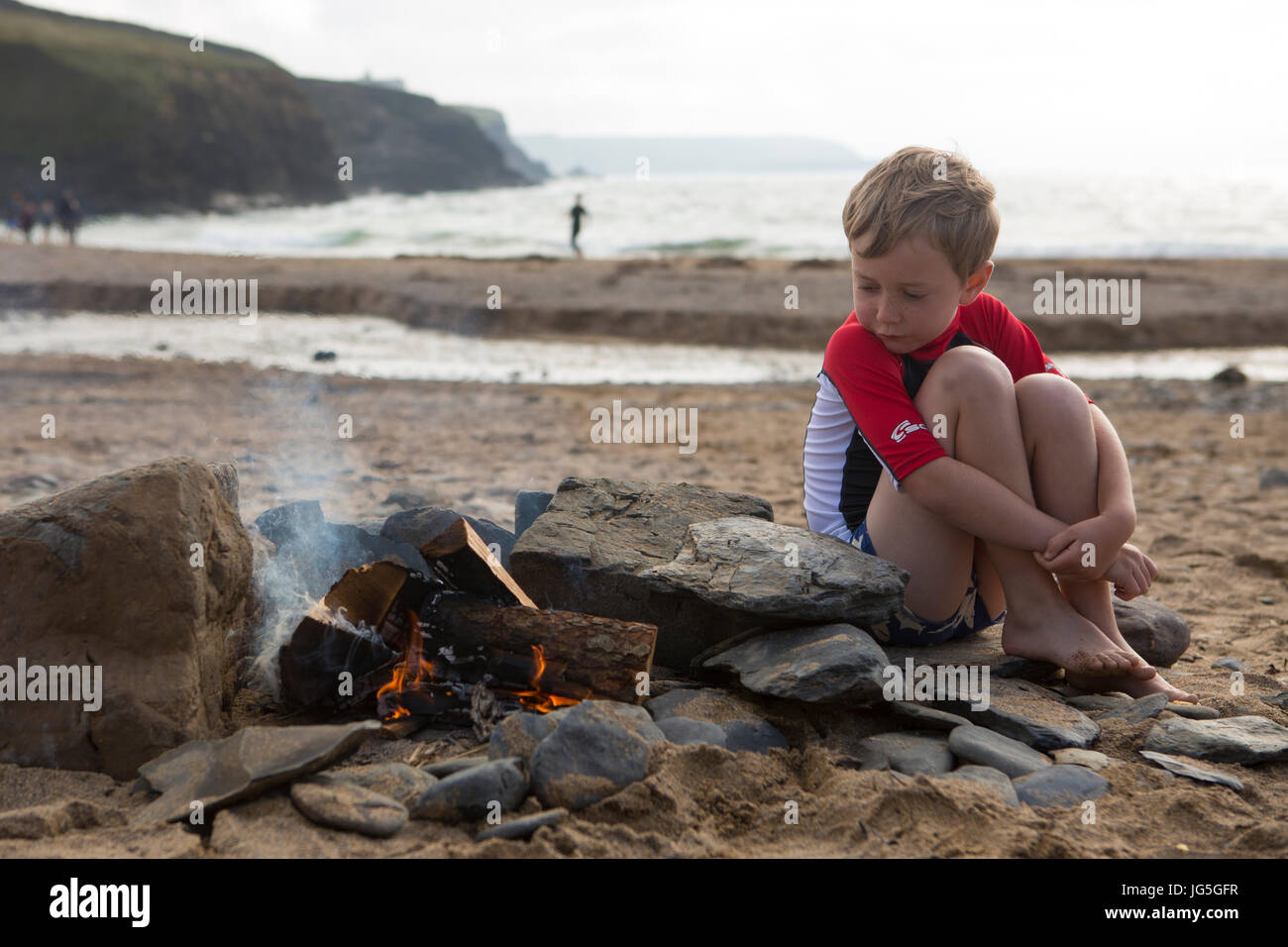 Ein Junge wacht über dem Strand Feuer im Urlaub, Cornwall, UK Stockfoto