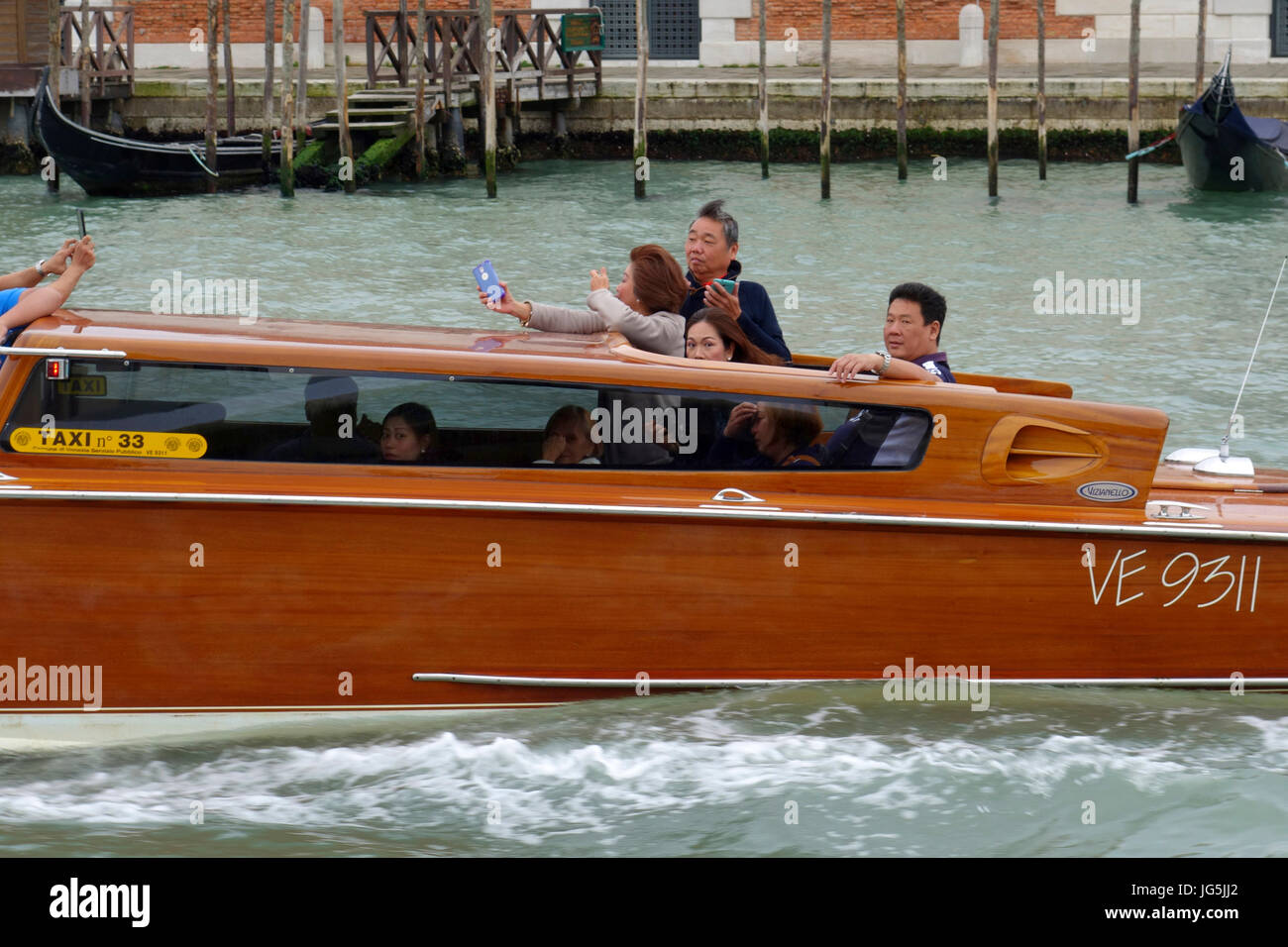 Asiatische Touristen genießen die Fahrt in einem taxi entlang des Canal Grande, Venedig, Italien Stockfoto