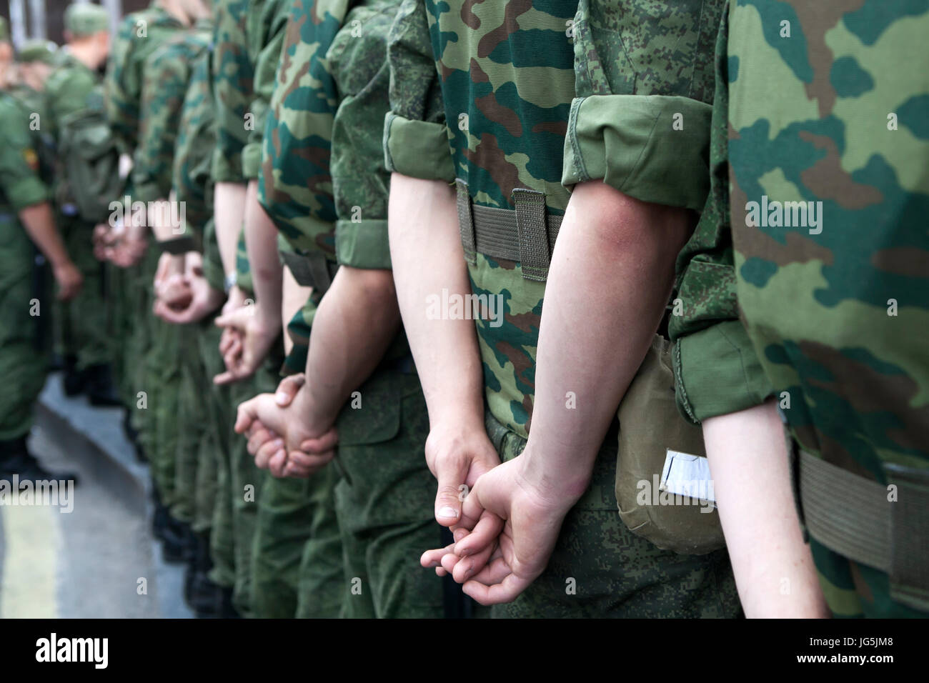 Hinten Sie Ansicht von. Soldaten in Tarnung Uniformen stehen auf die Manifestation, die Hände hinter dem Rücken. Stockfoto