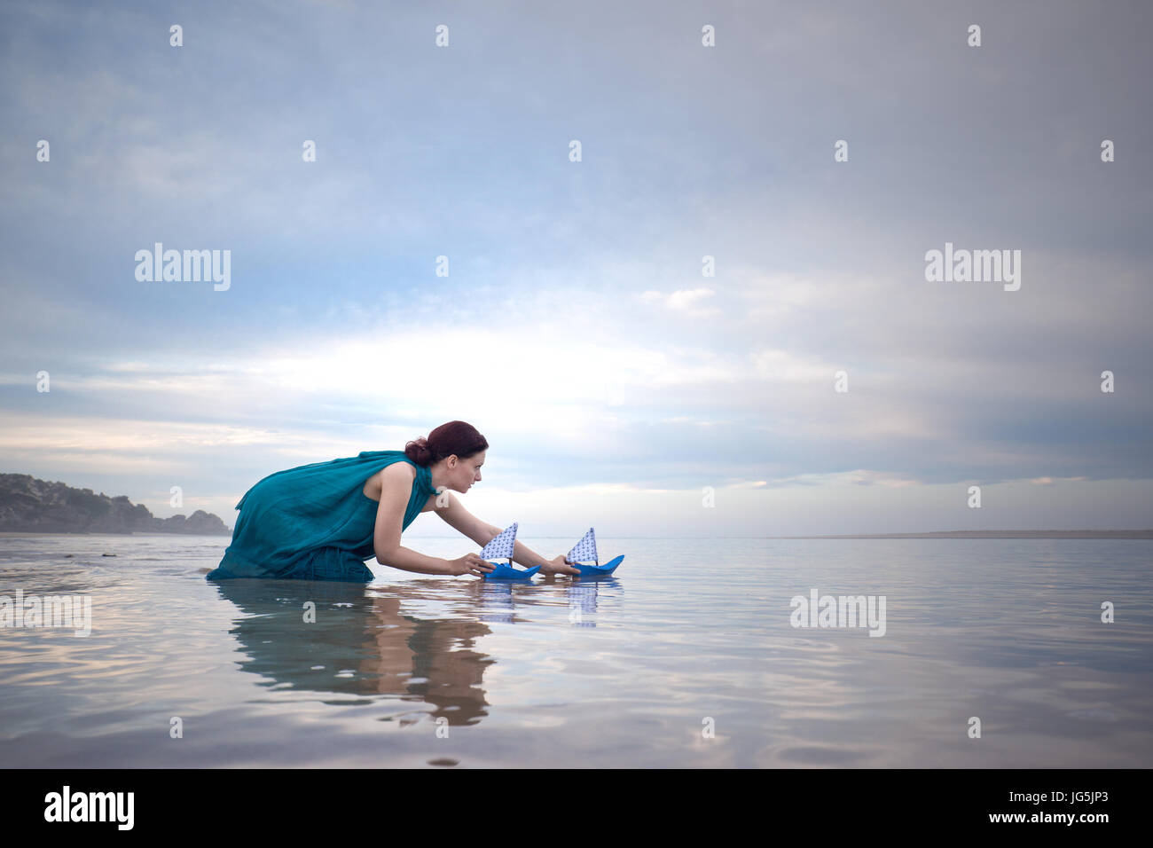 Frau mit blauem Papier Schiffe bei Ebbe am Strand Stockfoto