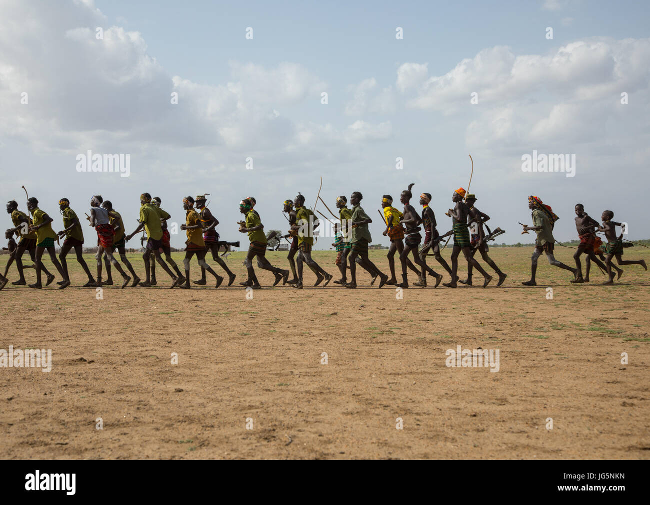 Männer, die im Einklang mit Waffen ausgeführt, während der Zeremonie stolz Ochsen in den Dassanech Stamm, Turkana County, Omorate, Äthiopien Stockfoto