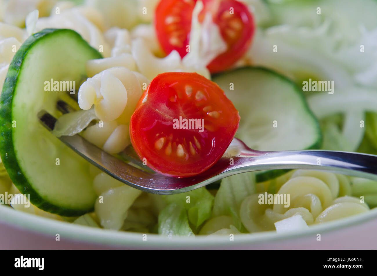 Nahaufnahme (Makro) einer Gabel, Pasta und Salat aus einer Schüssel heben.  Querformat (horizontale). Stockfoto