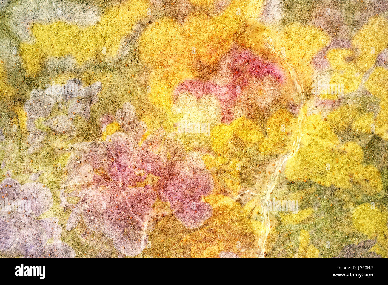 Abstrakte Hintergrundtextur aus einem Stück Stein, verstreut mit kleineren Steinen und überlagert mit leuchtend gelben, rosa und grünen Farbtönen. Stockfoto