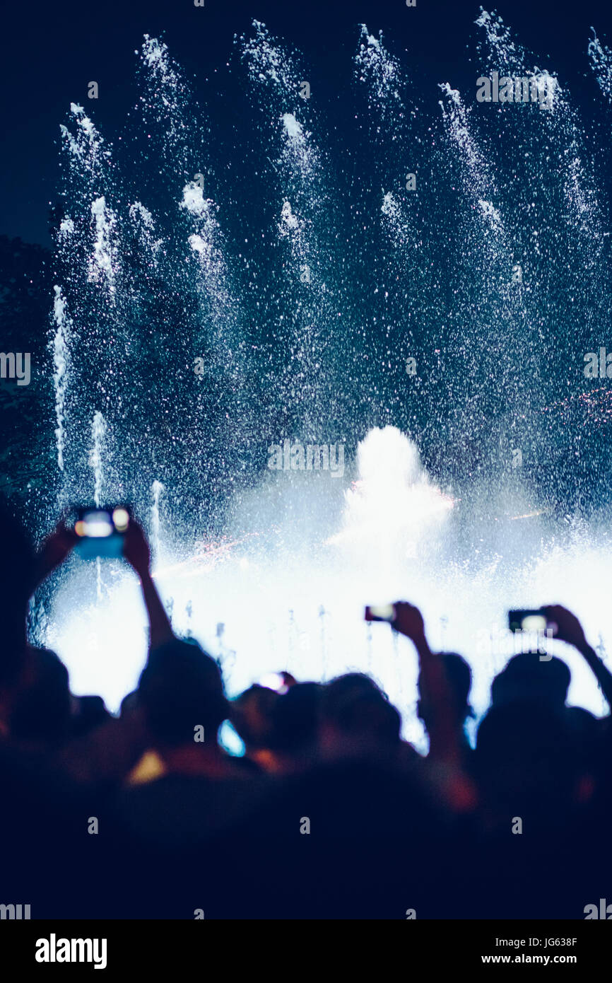 Menschen Fotografieren von Brunnen und Lichter mit Smartphones am Abend in der Innenstadt Stockfoto