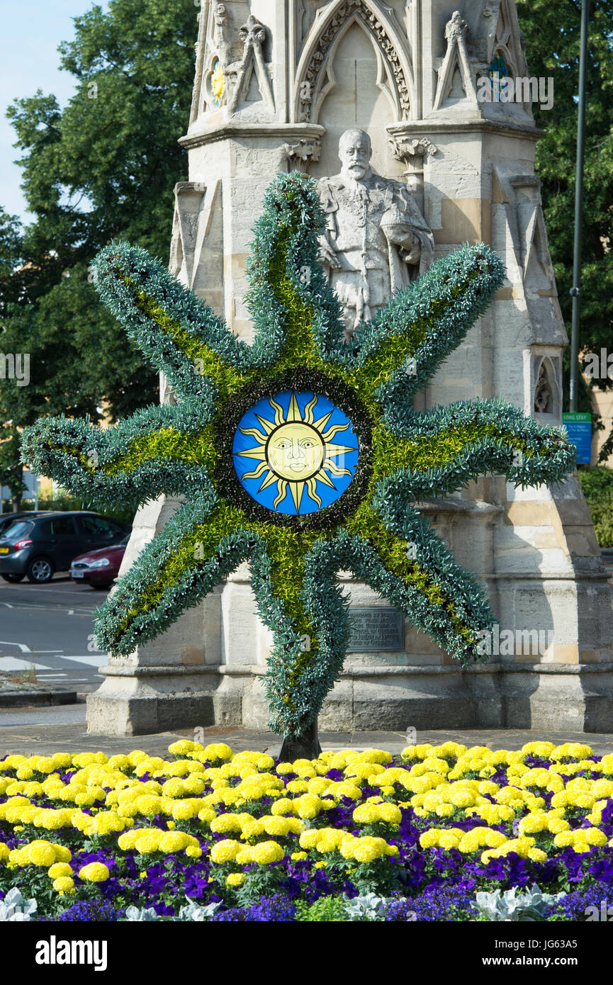 Floral Sonne Symbol Skulptur und bunten Blumenbeet vor Banbury cross, im Licht frühen Morgens. Oxfordshire, England Stockfoto