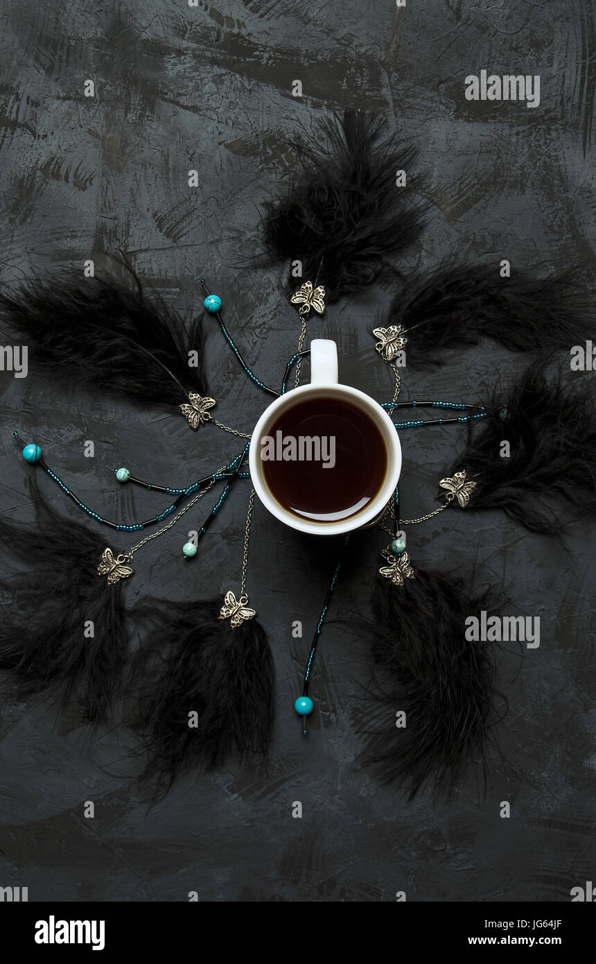 Kaffee auf dunklem Hintergrund mit schwarzen Federn Stockfoto
