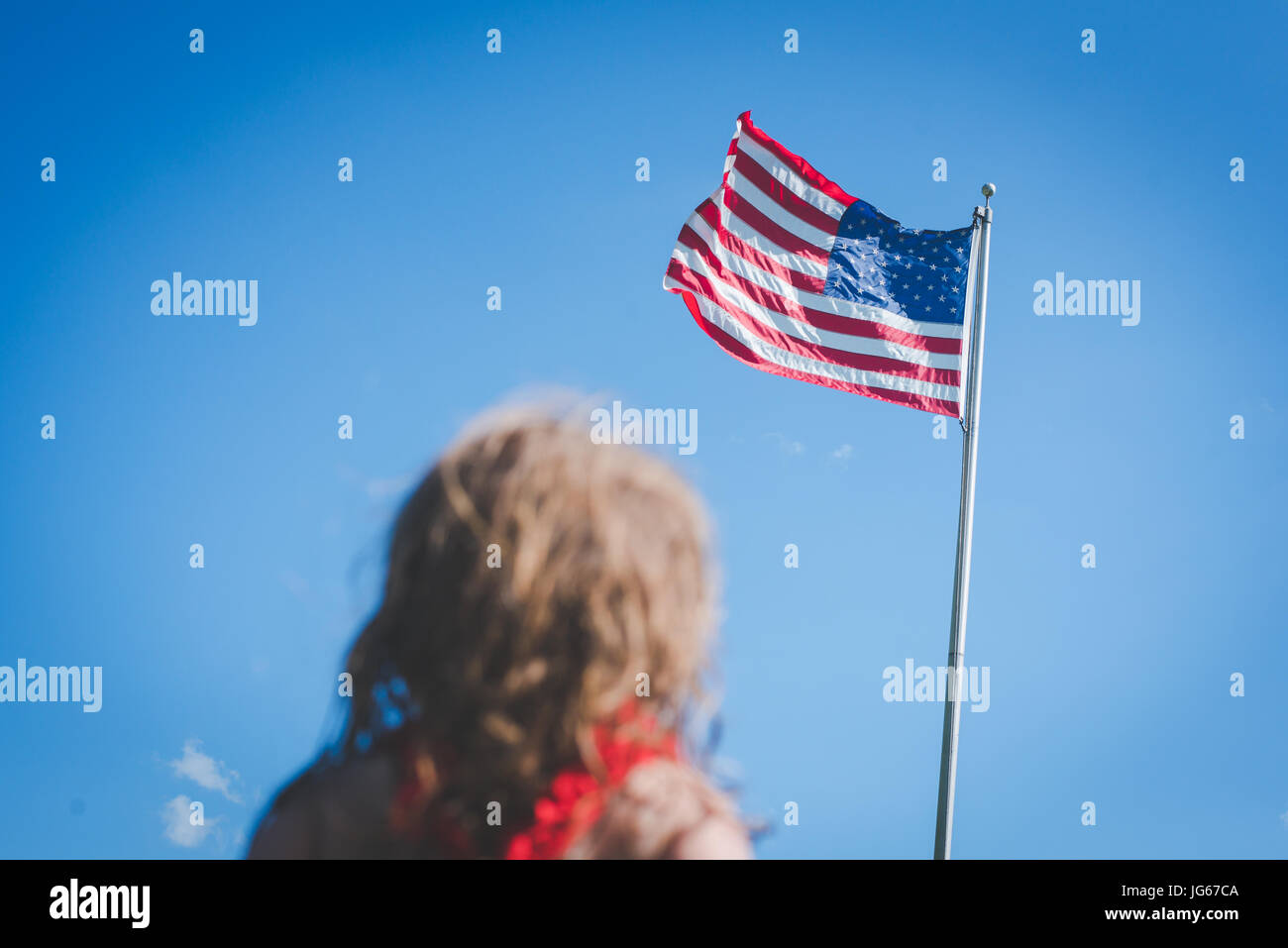 Ein junges Mädchen sucht an der amerikanischen Flagge. Stockfoto