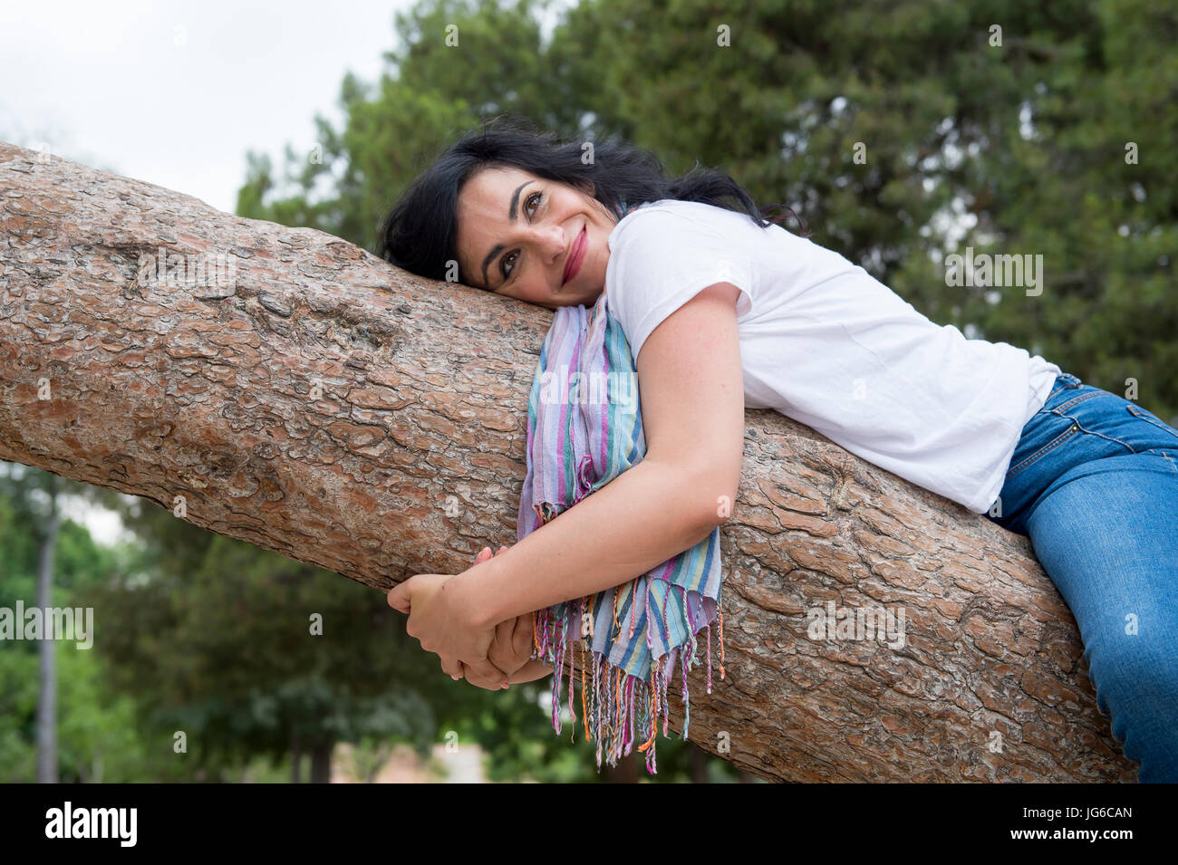 Sehr attraktive Frau kausale Kleidung tragen und umarmt einen Baum in einem grünen park Stockfoto