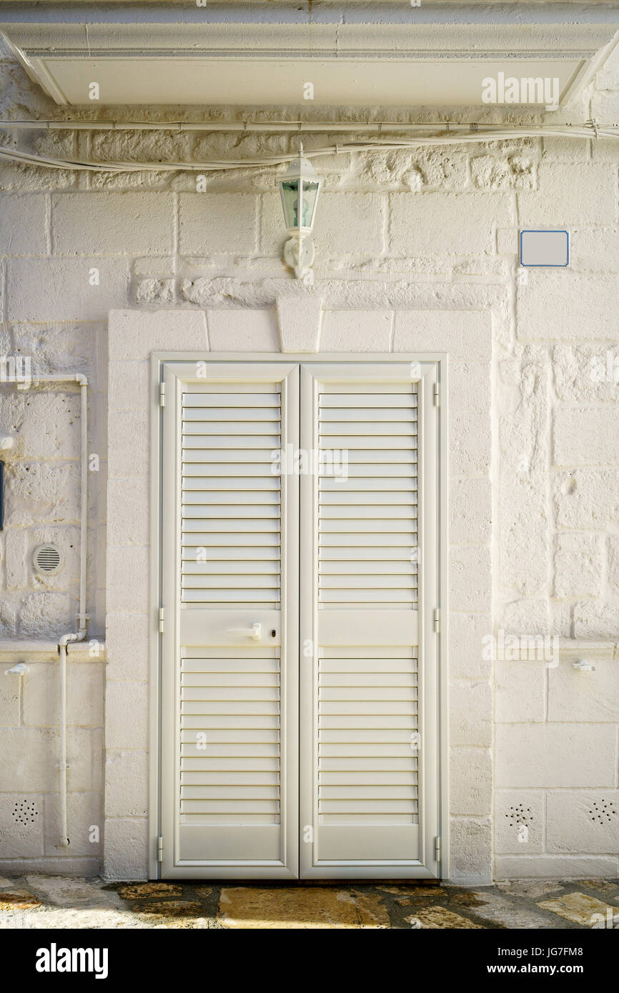 Eingangstür mit Fensterläden zum südlichen europäischen Haus, Italien Stockfoto