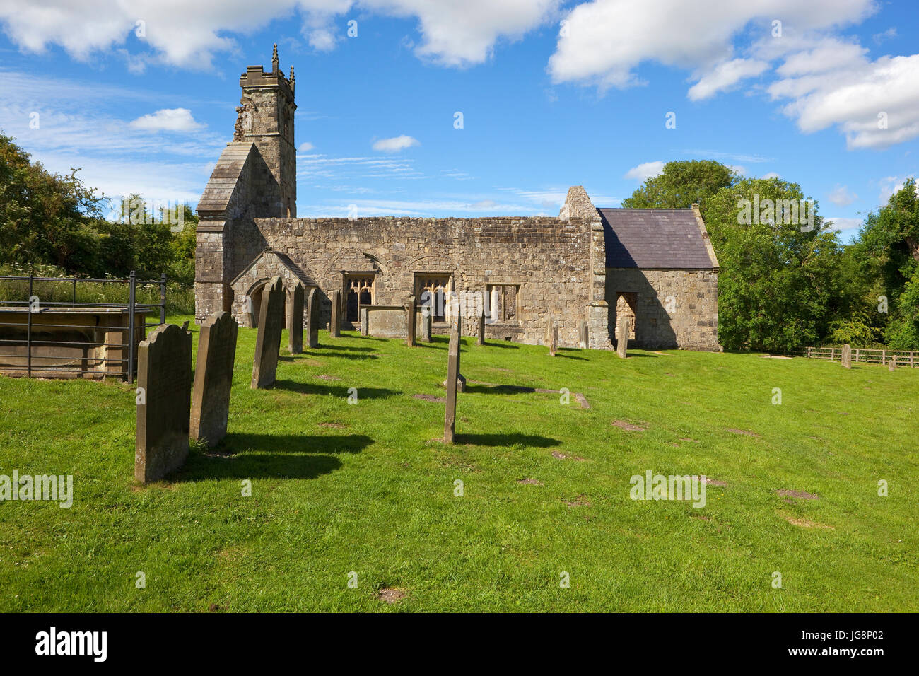 historische Wharram Percy mit Kirchenruinen und einem Friedhof bei blau bewölktem Himmel im Sommer Stockfoto