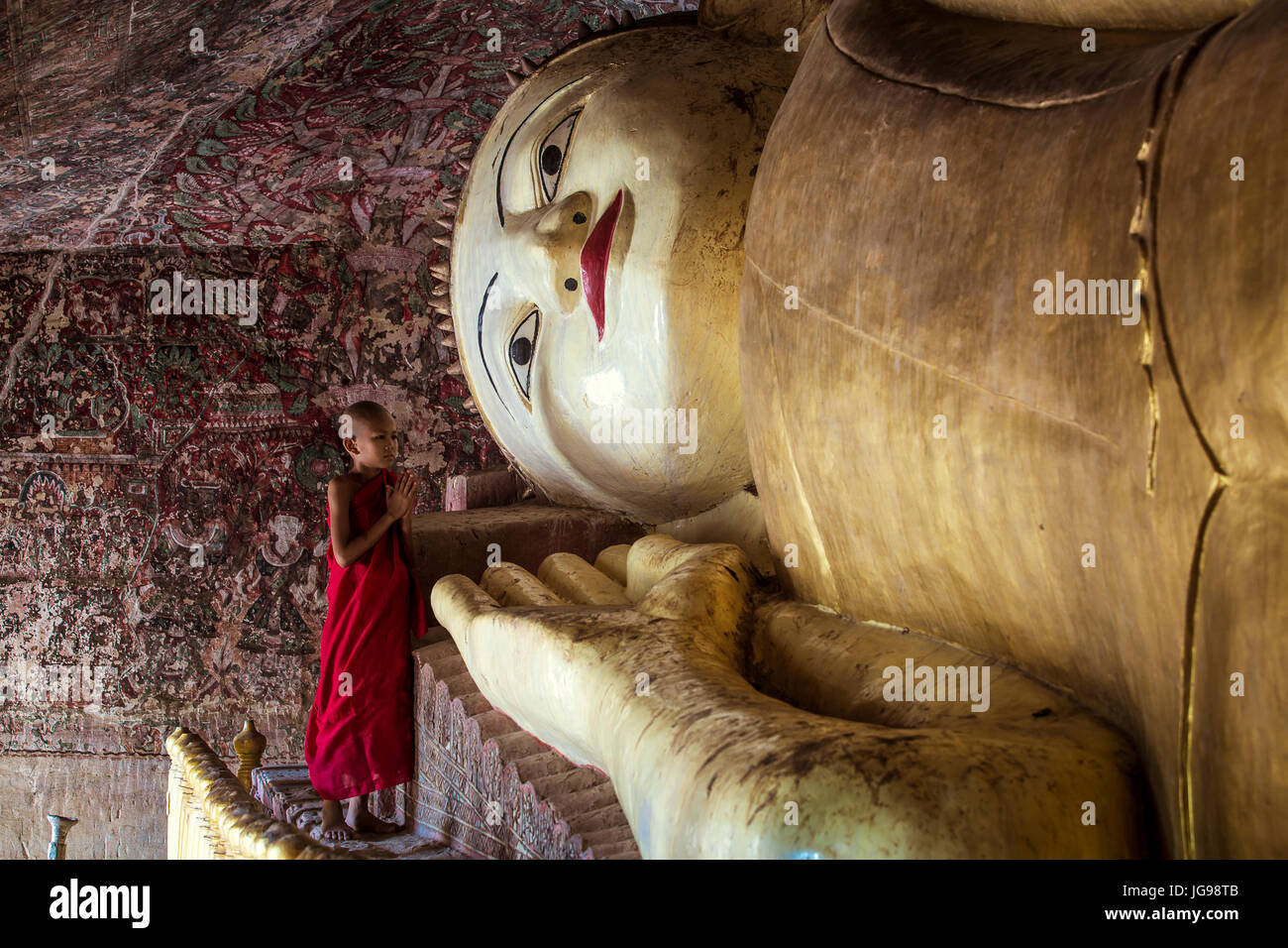 Buddhistischer Novize / kleinen Mönch / junger Mönch anbeten große schöne liegende Buddha-Statue in Phowintaung Höhle Monywa Myanmar Stockfoto
