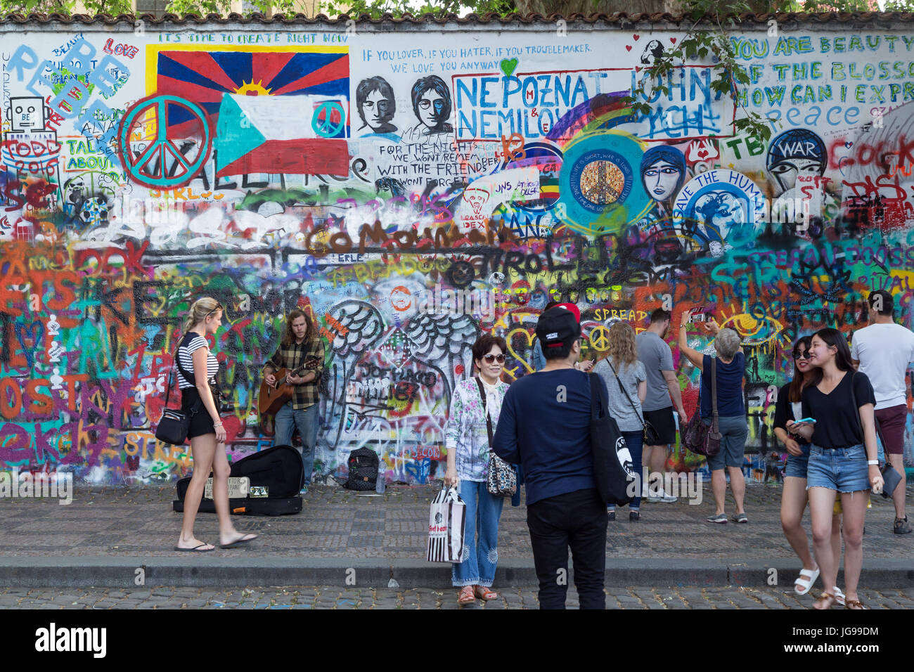 Viele Touristen und ein Straßenmusikant an der John-Lennon-Mauer in Prag. Es ist eine Wand mit Stücken von songtexte von Beatles Songs und John Lennon inspirierten Graffiti. Stockfoto