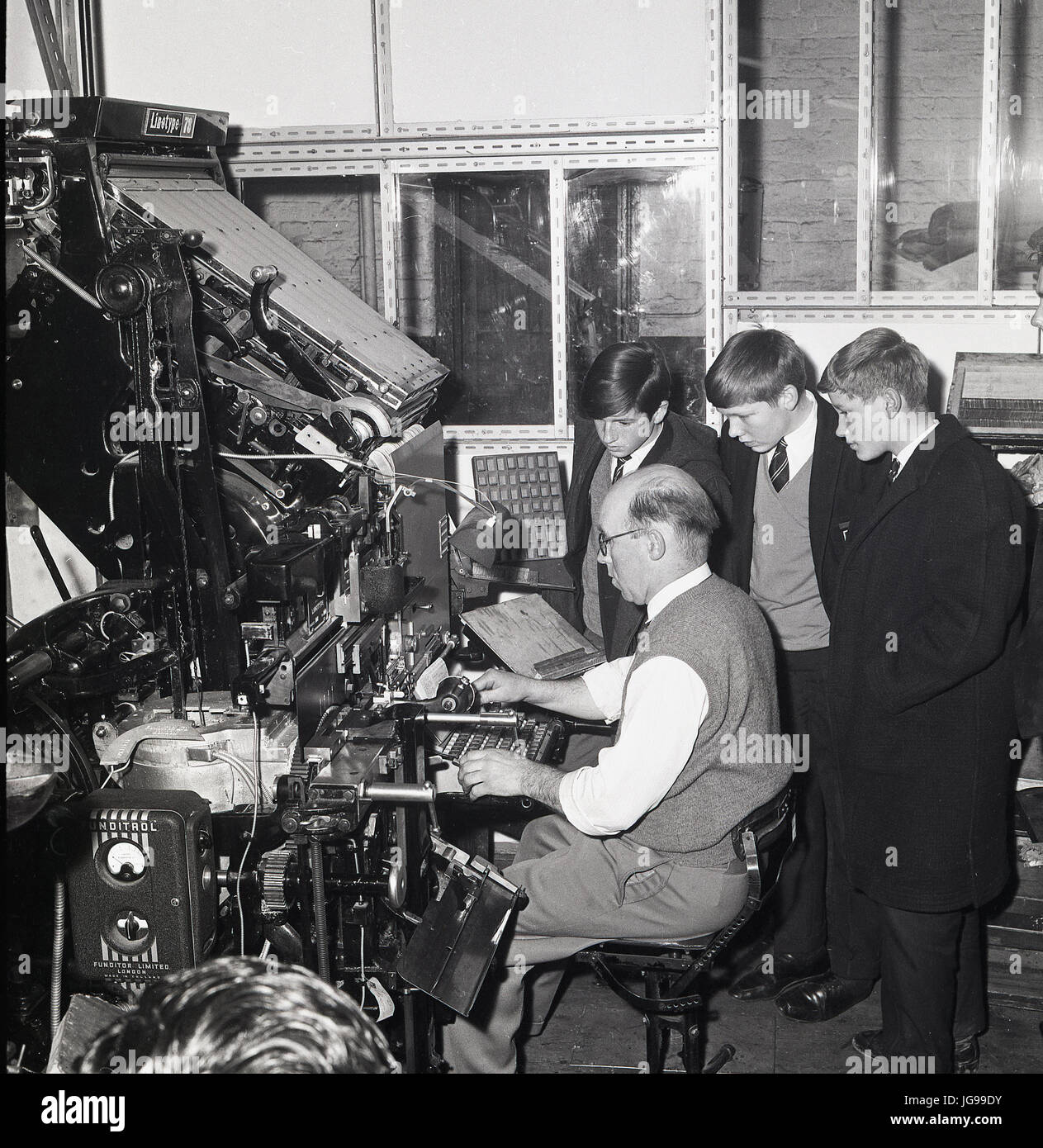 In den 1960er Jahren beobachten drei Schuljungen einen Zeitungsstypsetter oder Compositor bei der Arbeit bei einem Besuch der Druckmaschinen der Londoner South East und der englischen Zeitung Kentish Mercury. Stockfoto