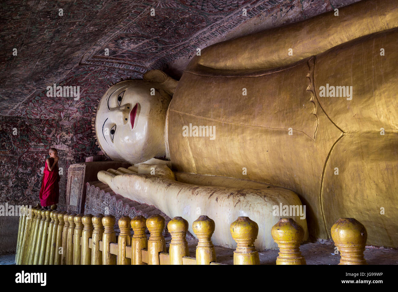 Buddhistischer Novize / kleinen Mönch / junger Mönch anbeten große schöne liegende Buddha-Statue in Phowintaung Höhle Monywa Myanmar Stockfoto