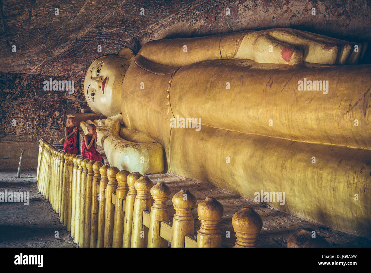 Buddhistischer Novize / kleinen Mönch / junger Mönch anbeten große schöne liegende Buddha-Statue in Phowintaung Höhle Monywa Myanmar Stockfoto