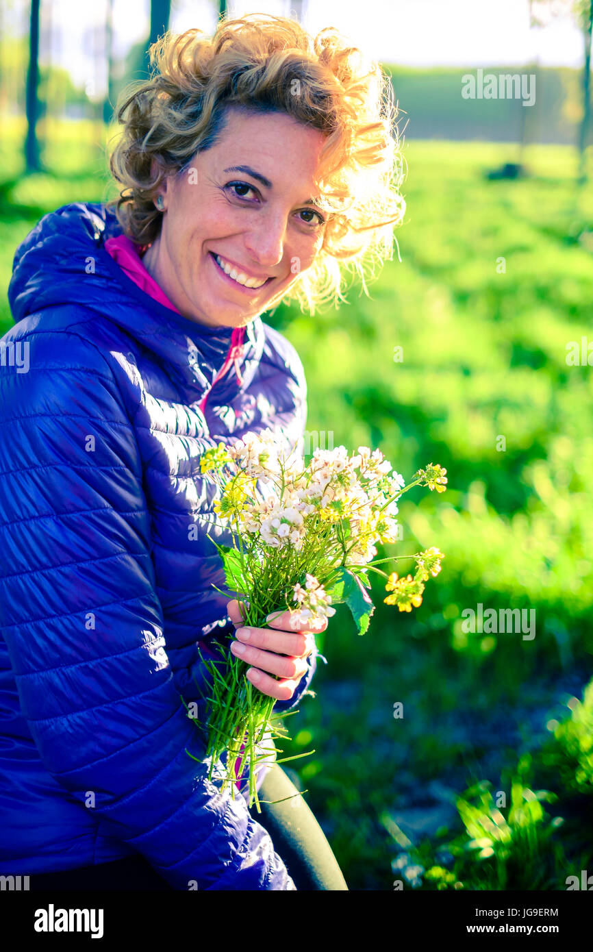 Junge Frau mit einem Haufen Blumen Stockfoto