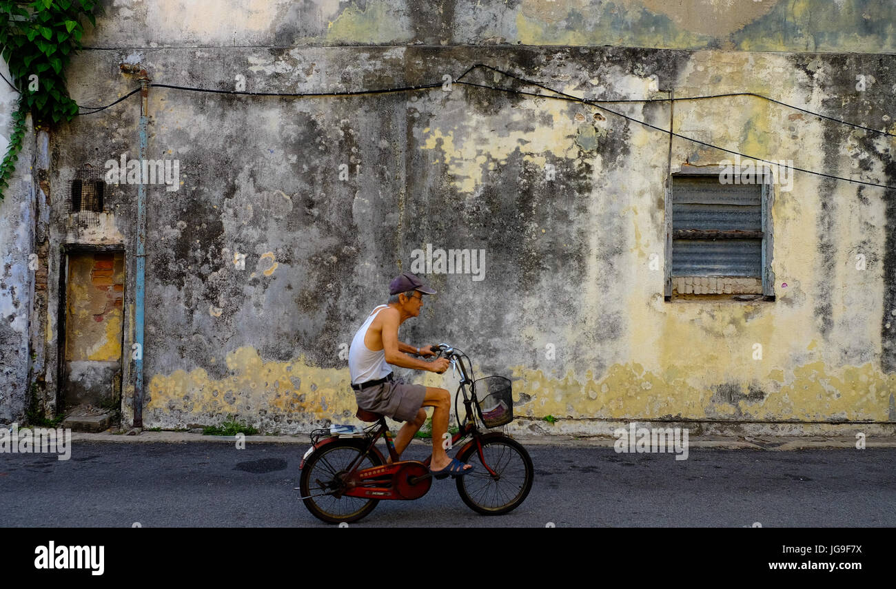 Ein Mann fährt Rad auf einer Straße in Georgetown, Penang, Malaysia Stockfoto