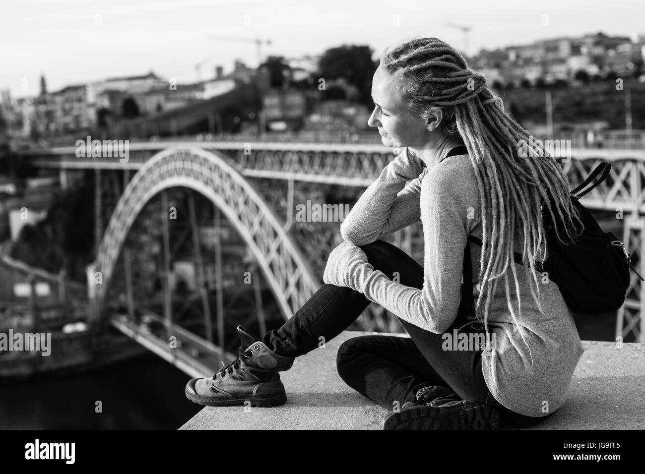 Schwarz / weiß-Foto der jungen Frau mit Dreadlocks, sitzen auf dem Hintergrund der Dom Luis ich in Porto, Portugal zu überbrücken. Stockfoto