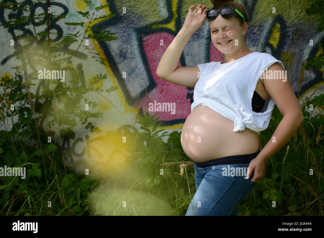 Glückliche junge Teenager Schwangere mit Sonnenbrille frech in die Kamera schauen Stockfoto